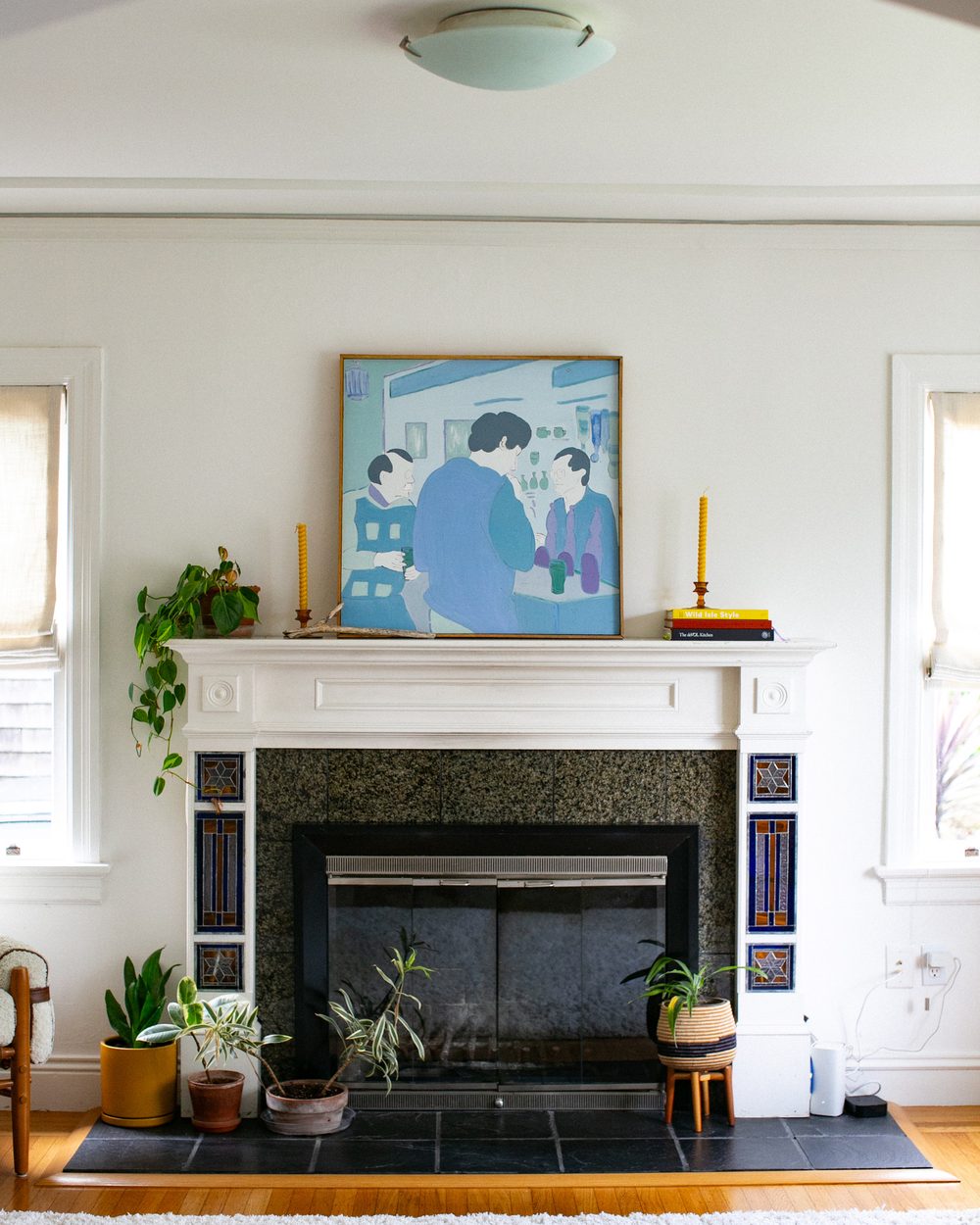 Fireplace mantel styled with art, candles and plants