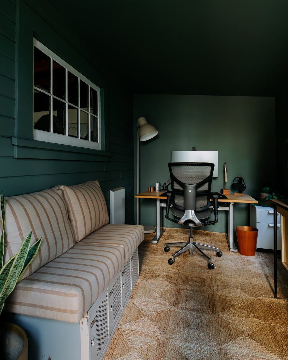 Deep green home office with a striped bench and standing desk