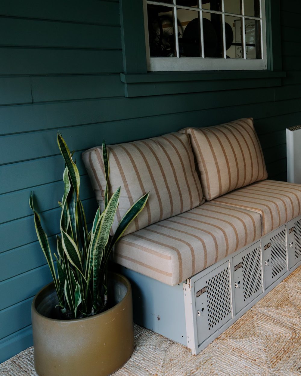 Striped cushion bench on vintage lockers beside a snake plant