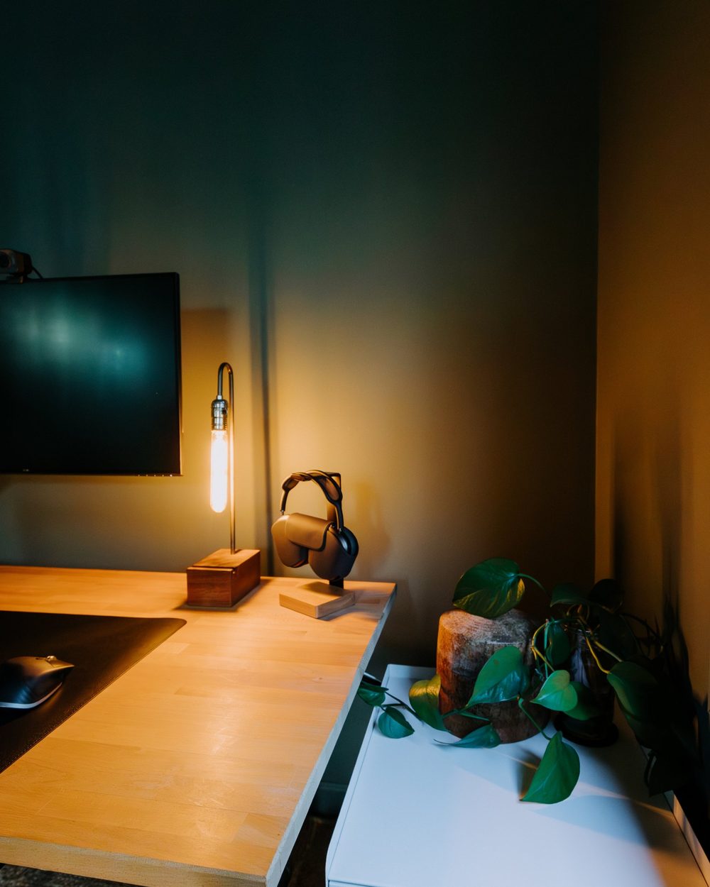 Warm desk lamp glowing against a dark green wall